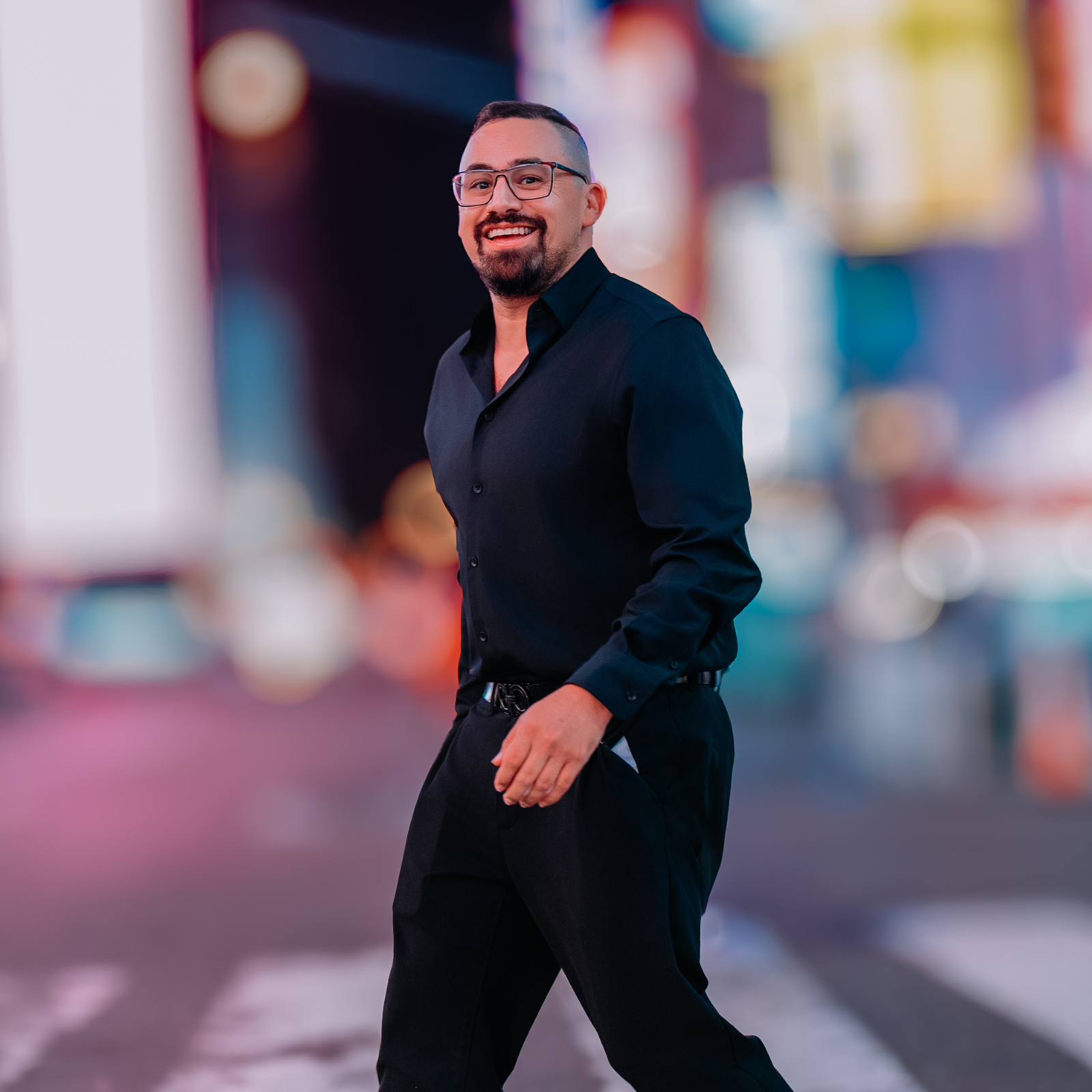 Ryan Salinas smiling in a black shirt in a colorful city street