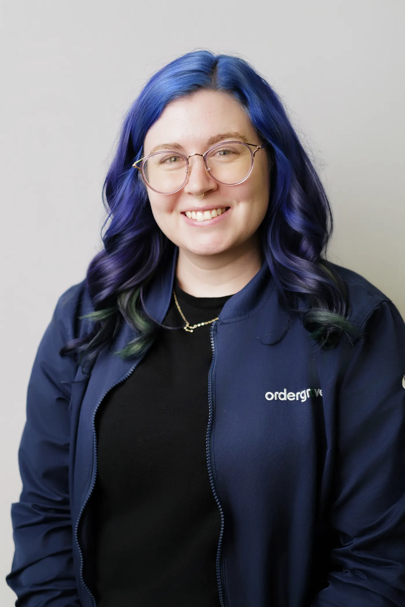 Professional headshot of a woman in a dark jacket against a light studio background